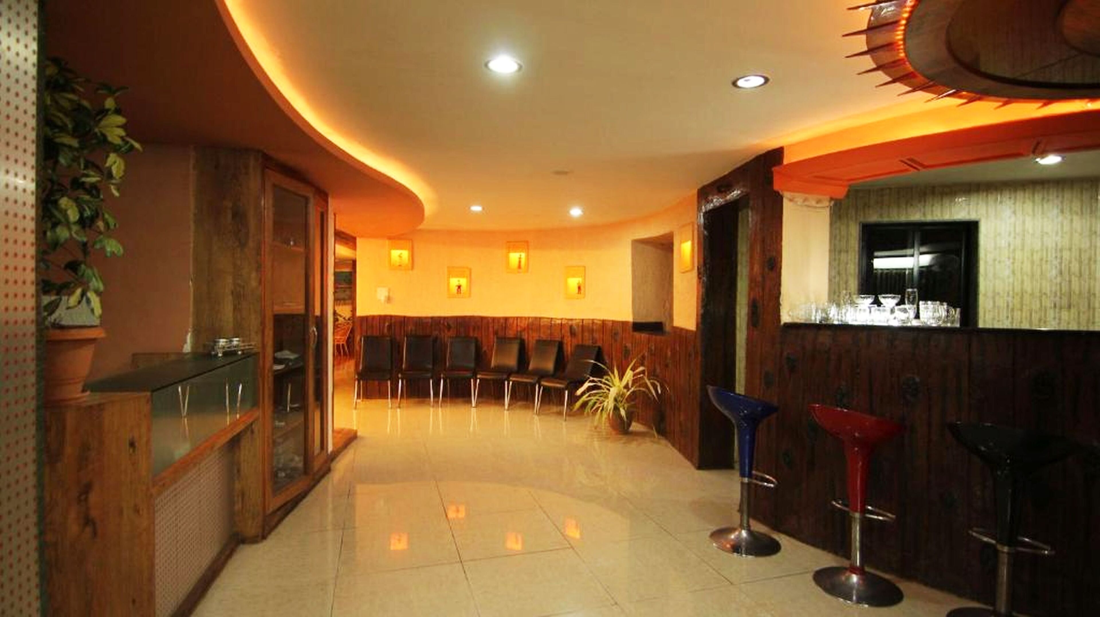 A hotel lobby with a reception desk, seating area, and bar stools.