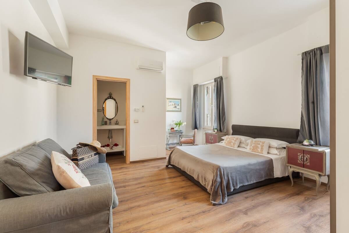 A bedroom with a bed, a sofa, a TV, and a wardrobe.