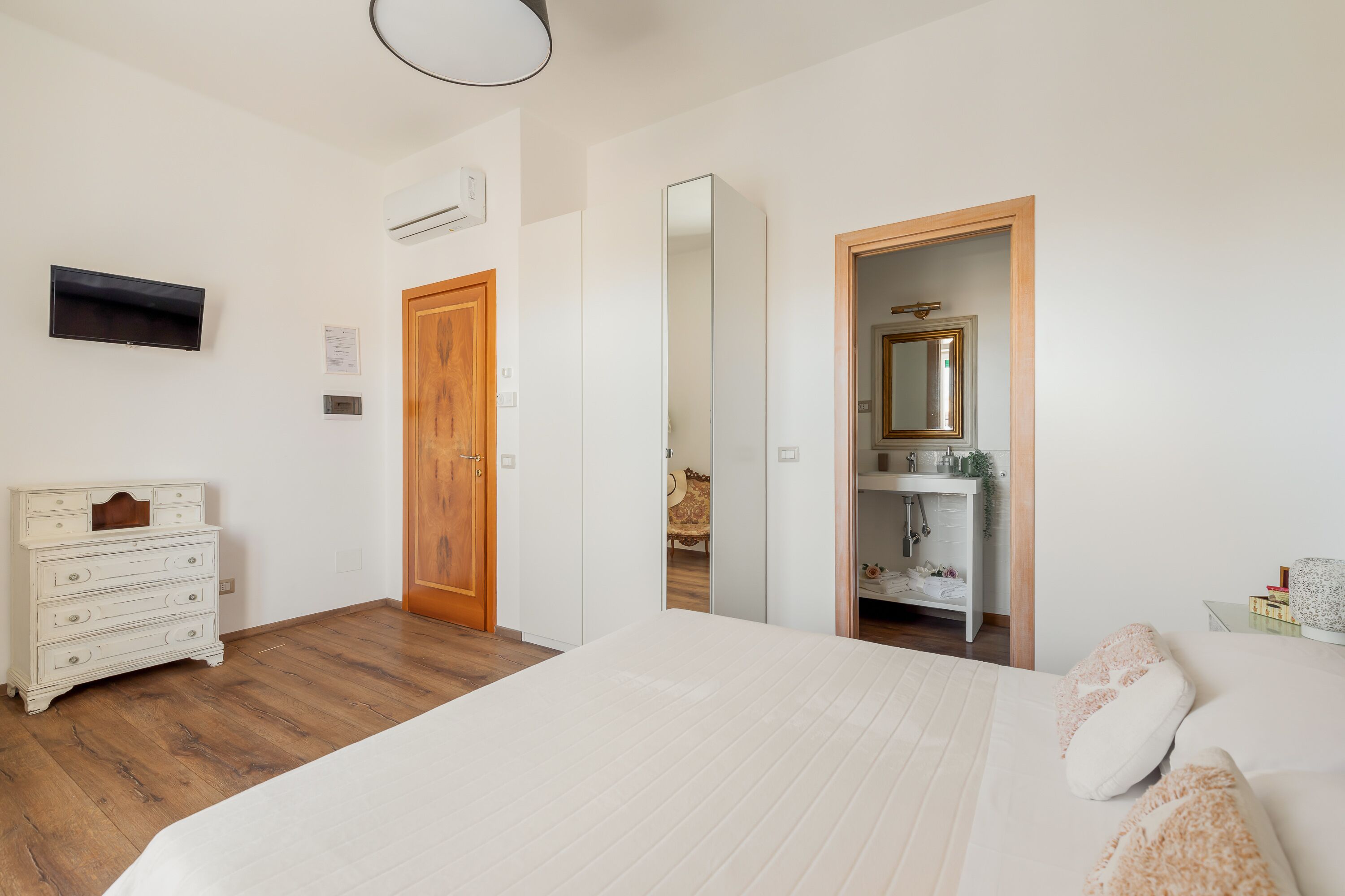 A bedroom with a bed, dresser, and a mirror.