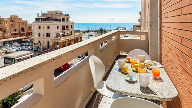 A balcony with a table set for breakfast, overlooking a cityscape and the sea. - Guest House Maison 6 (Rome)