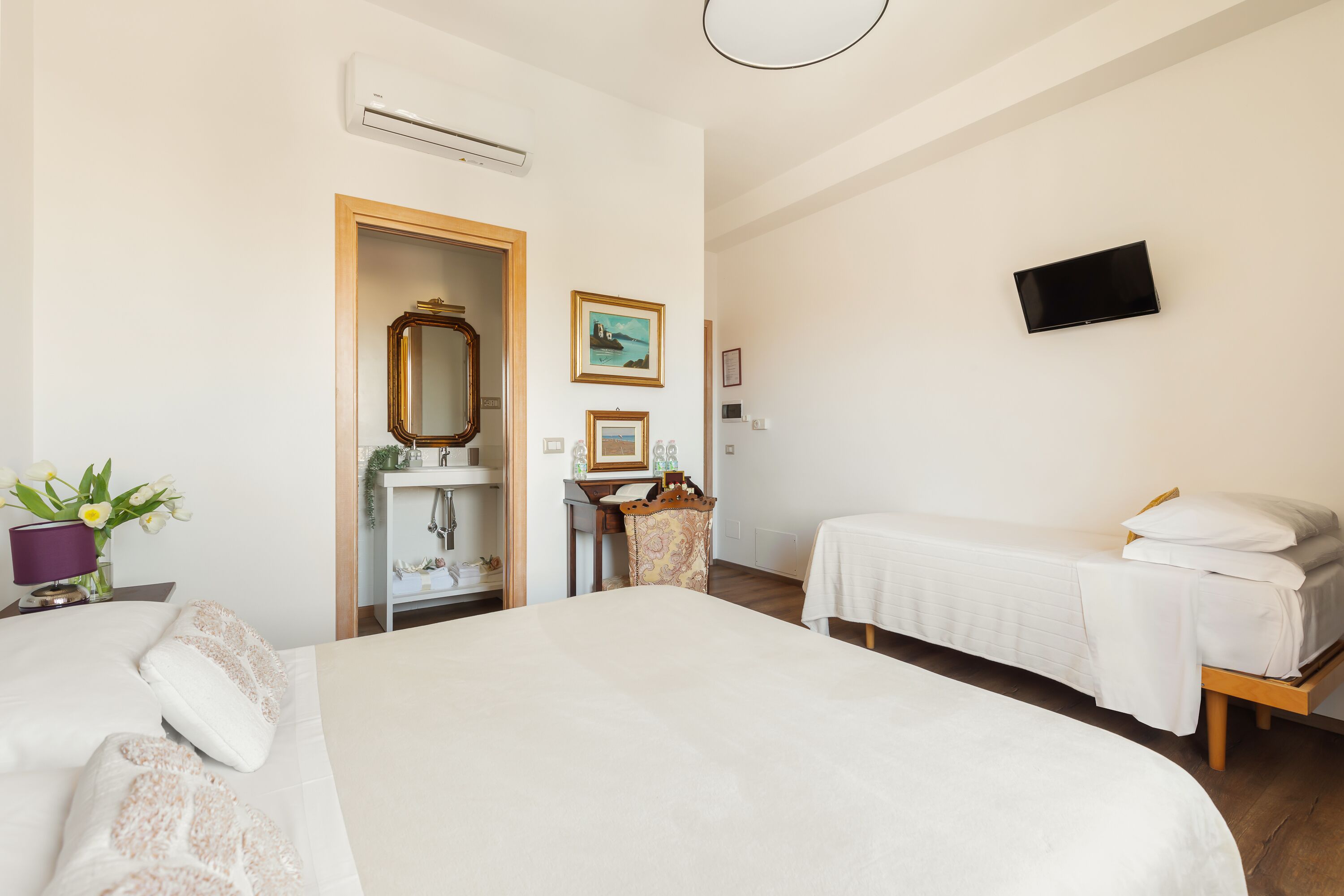Une chambre d’hôtel avec deux lits, une télévision, un miroir et un petit bureau avec une chaise.