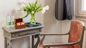 A room with a framed painting, a table with a vase of flowers, a chair, and a window with a curtain. - Guest House Maison 6 (Rome)