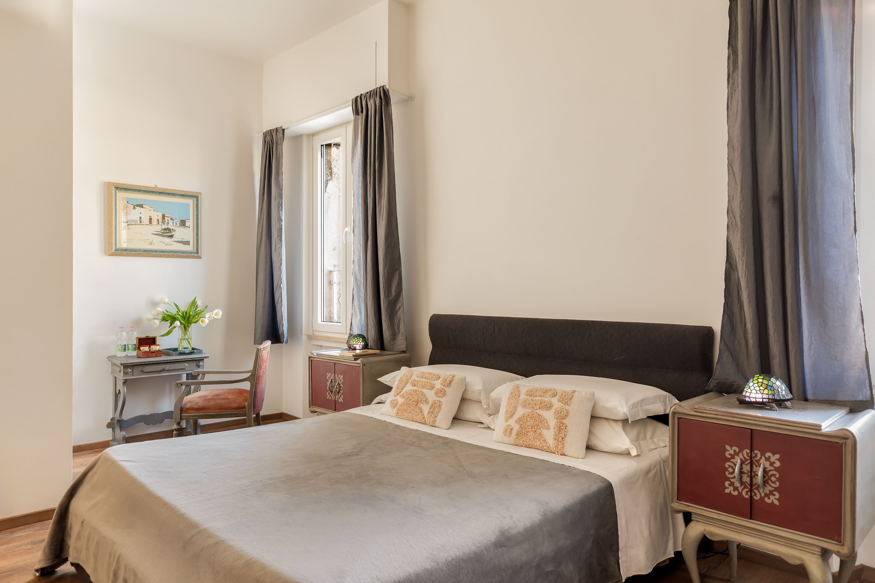 A bedroom with a bed, a nightstand, a desk, and a chair.