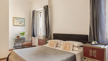 A bedroom with a bed, a nightstand, a desk, and a chair.