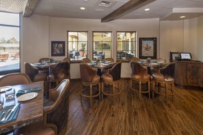 A restaurant with wooden flooring, leather chairs, and large windows offering views of the outdoor seating area. - The Murieta Inn & Spa (Sloughhouse)