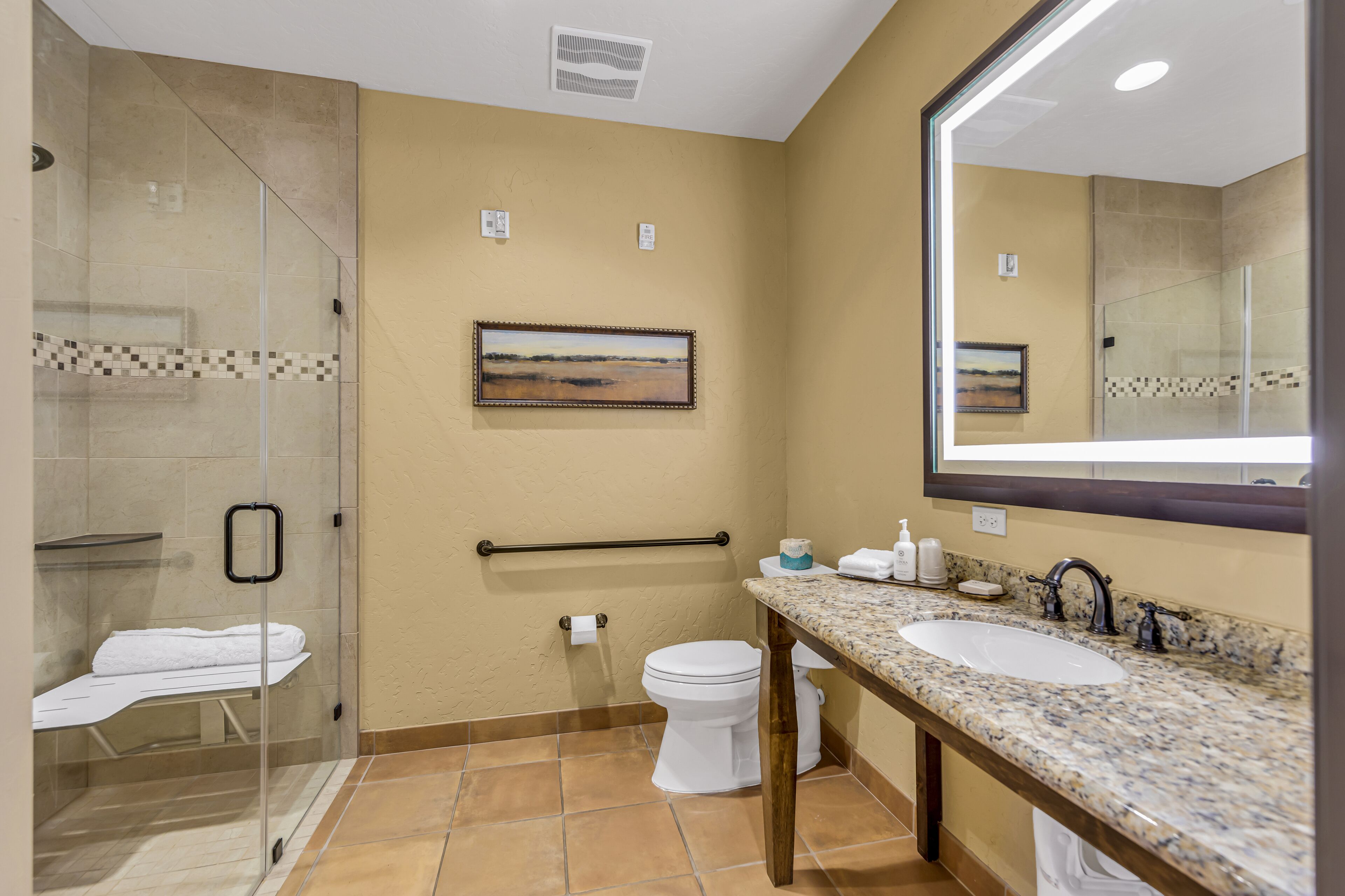 Une salle de bain avec une douche à parois de verre, un lavabo, des toilettes et un tableau encadré au mur.