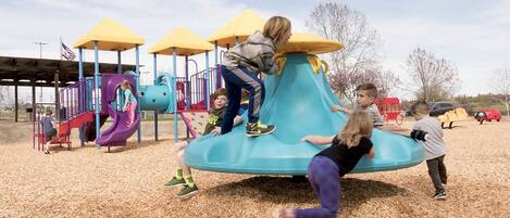 A playground with a slide, climbing structures, and a covered area with yellow canopies.