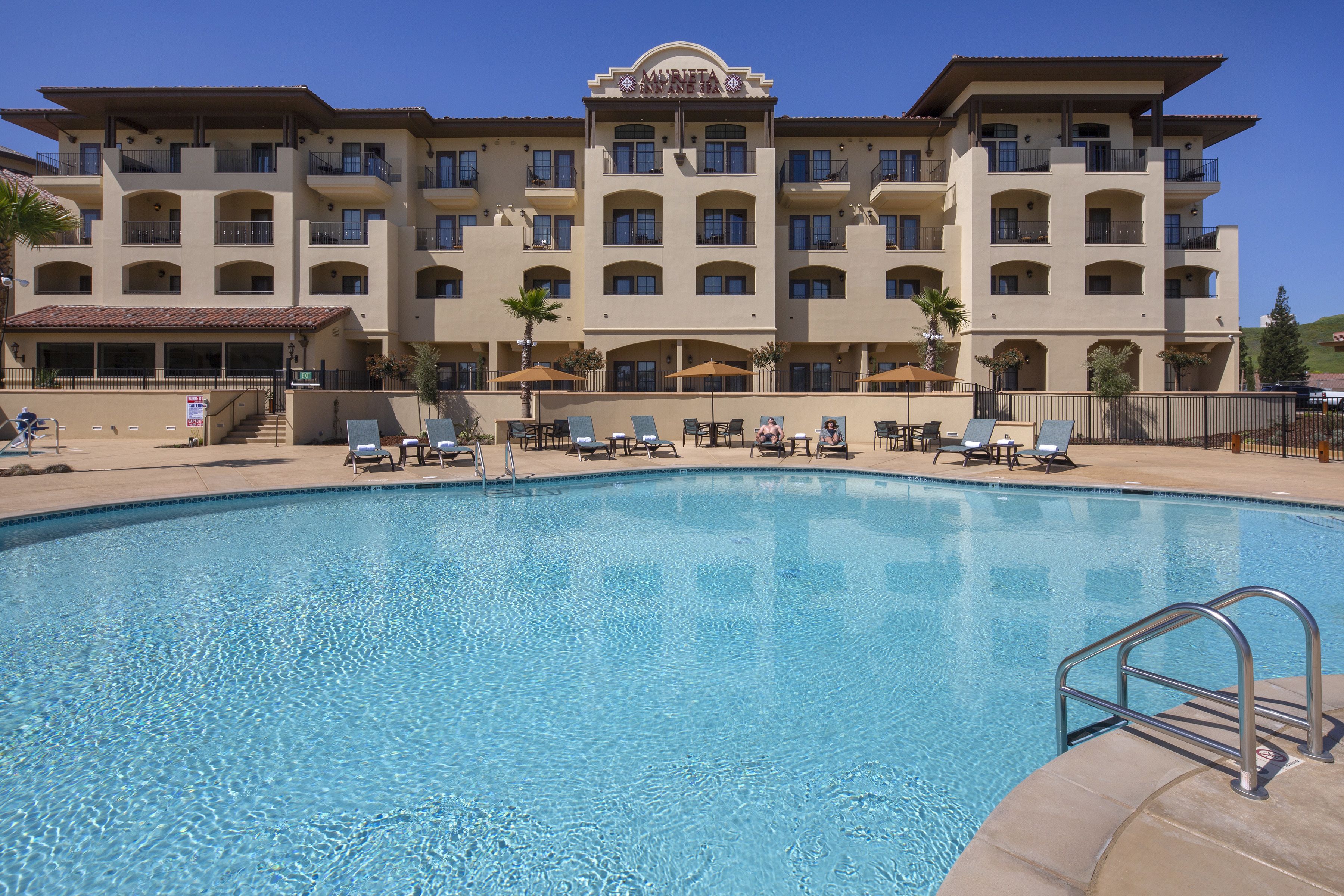Um hotel com piscina, várias varandas e áreas de estar ao ar livre.