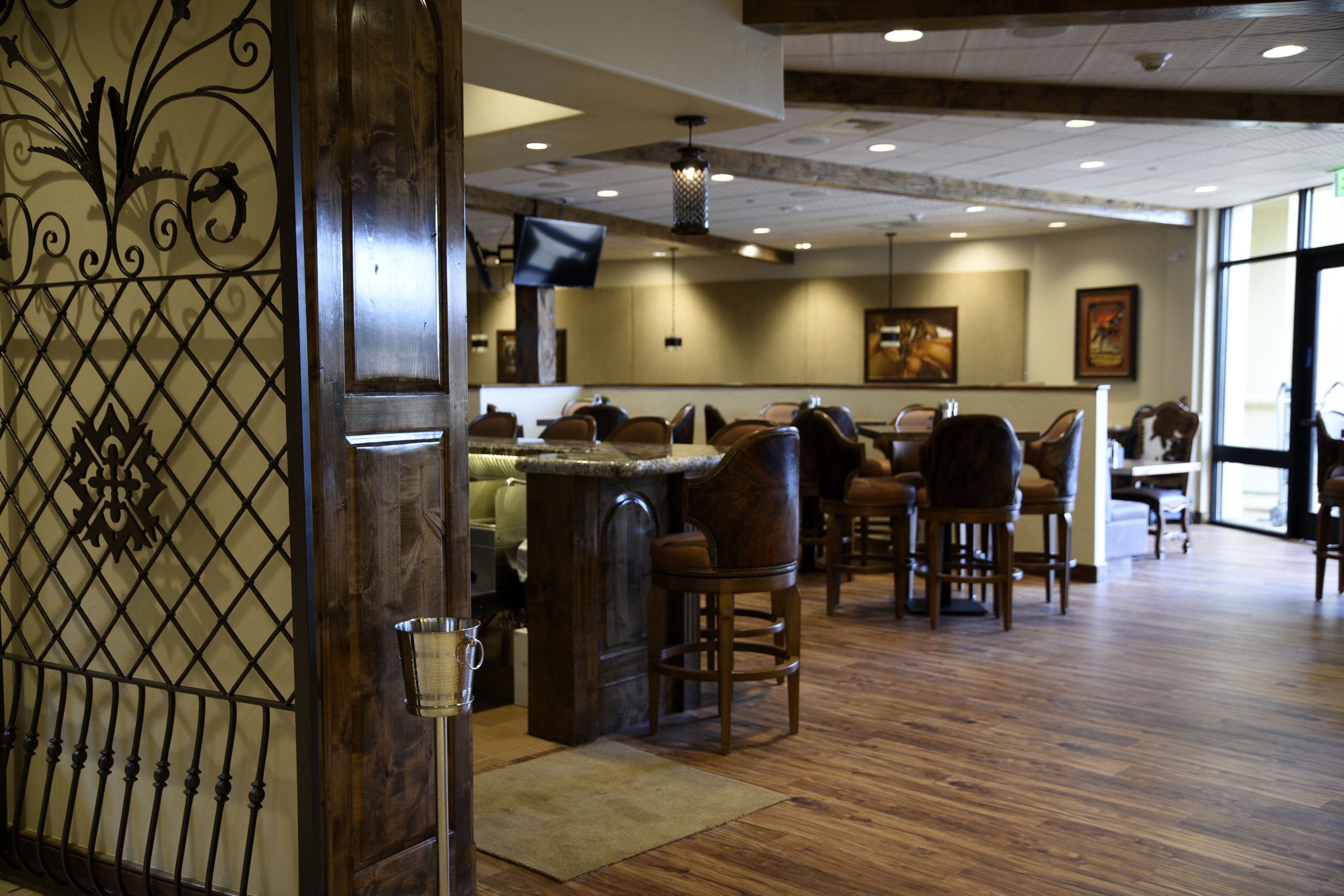 A restaurant interior with wooden flooring, bar stools, and a television mounted on the wall.