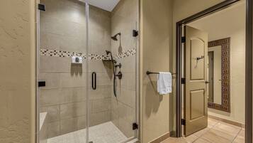 Un baño moderno con cabina de ducha de vidrio, baldosas color beige y un borde decorativo de azulejos.