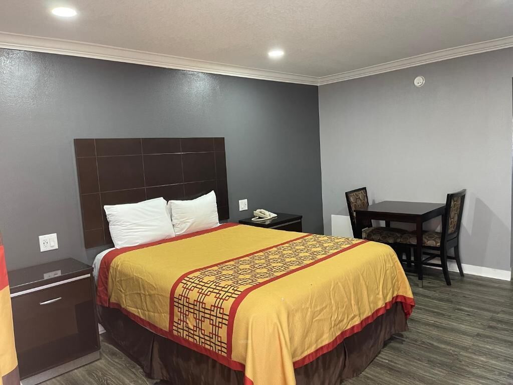 A hotel room with a bed, a bedside table, a chair, and a small table.