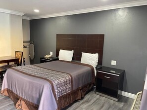 Una habitación de hotel con una cama grande, una mesita de noche y una silla.
