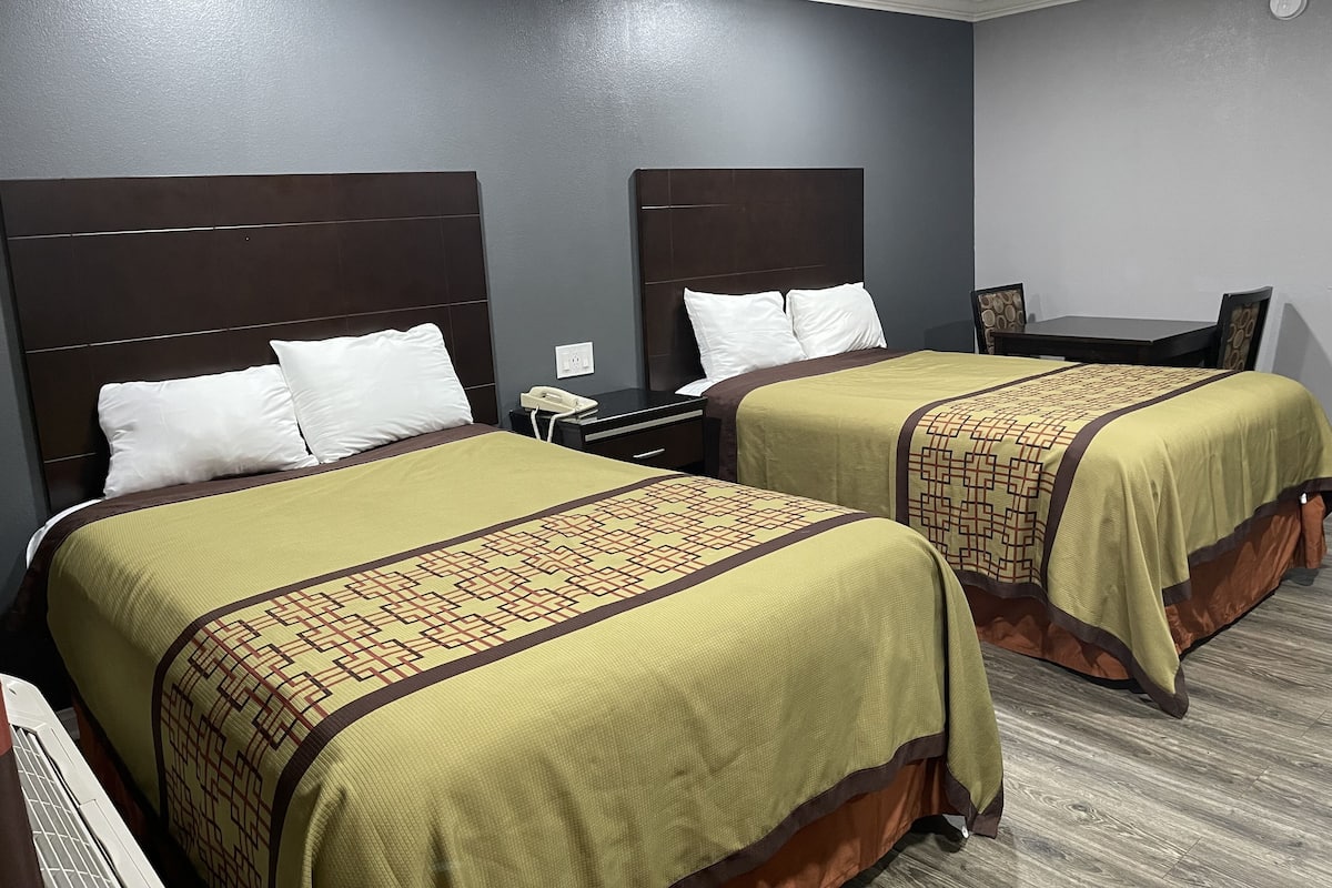 A hotel room with two beds, a desk, and a chair.