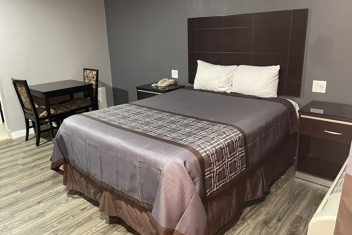 A hotel room with a large bed, a desk, and a chair.
