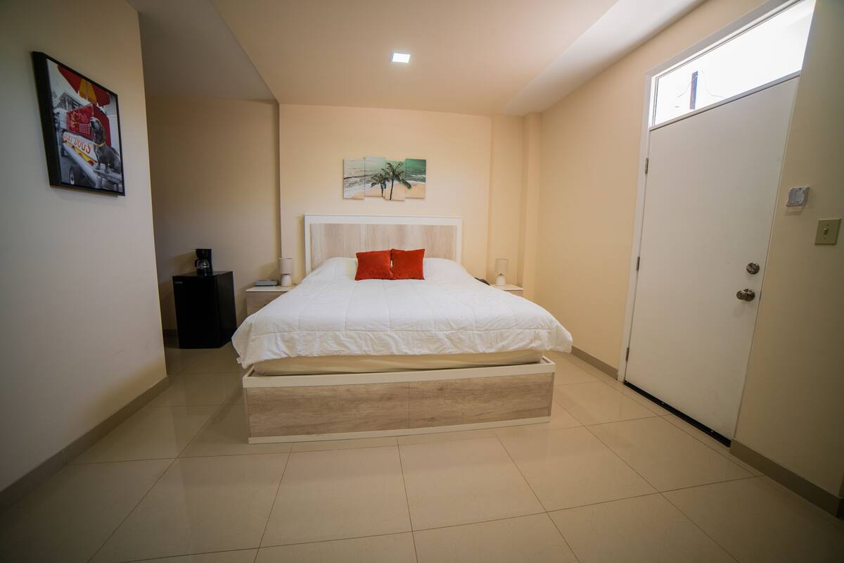 A bedroom with a bed, a nightstand, a lamp, a painting, and a wardrobe.