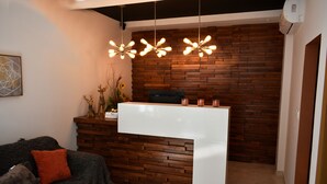 Een receptiezone met een houten wand, een wit receptiebalie en een bank met een rode kussen.