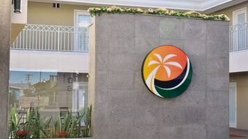 A building with a concrete wall featuring a logo and a balcony with a white railing.