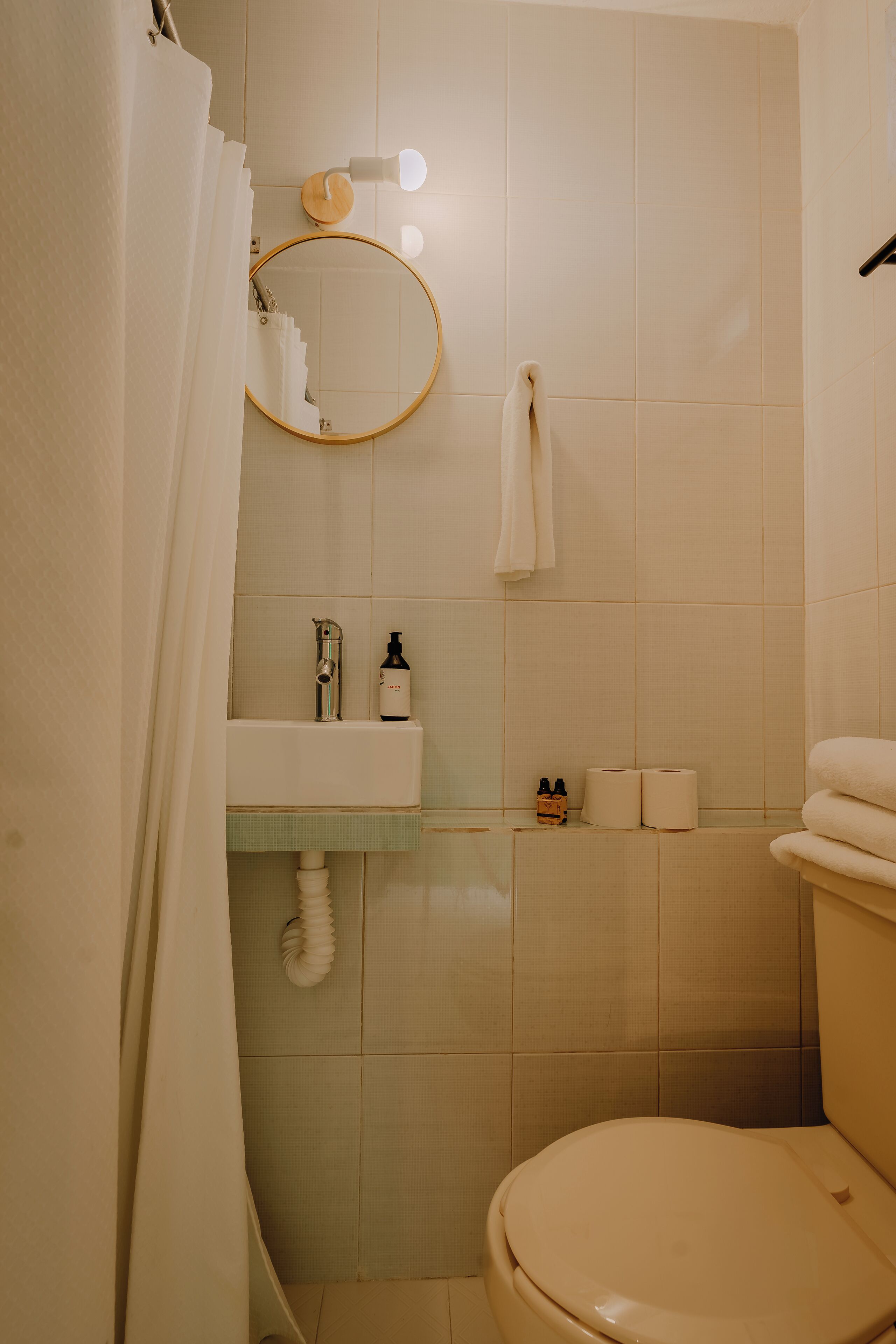 A bathroom with a toilet, sink, and mirror.
