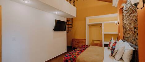 Un dormitorio con una cama de madera, un televisor, una escalera y una pared de ladrillo.