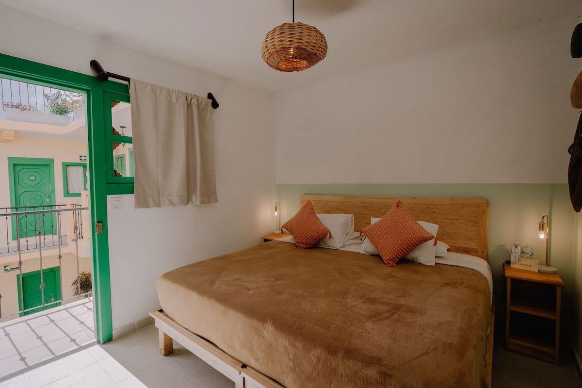 Un dormitorio con cama, mesita de noche, lámpara colgante y vistas al exterior.