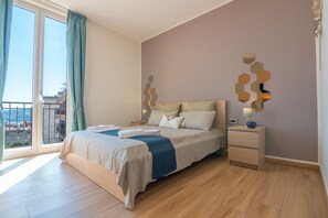 Une chambre à coucher avec un lit, une table de chevet et une vue sur l’extérieur grâce à une grande fenêtre.