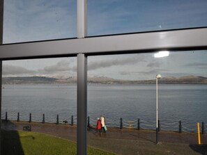 A view of a body of water with a distant mountain range, a pedestrian path, and a lamp post. - Waterfront Guest Accommodation (Greenock)