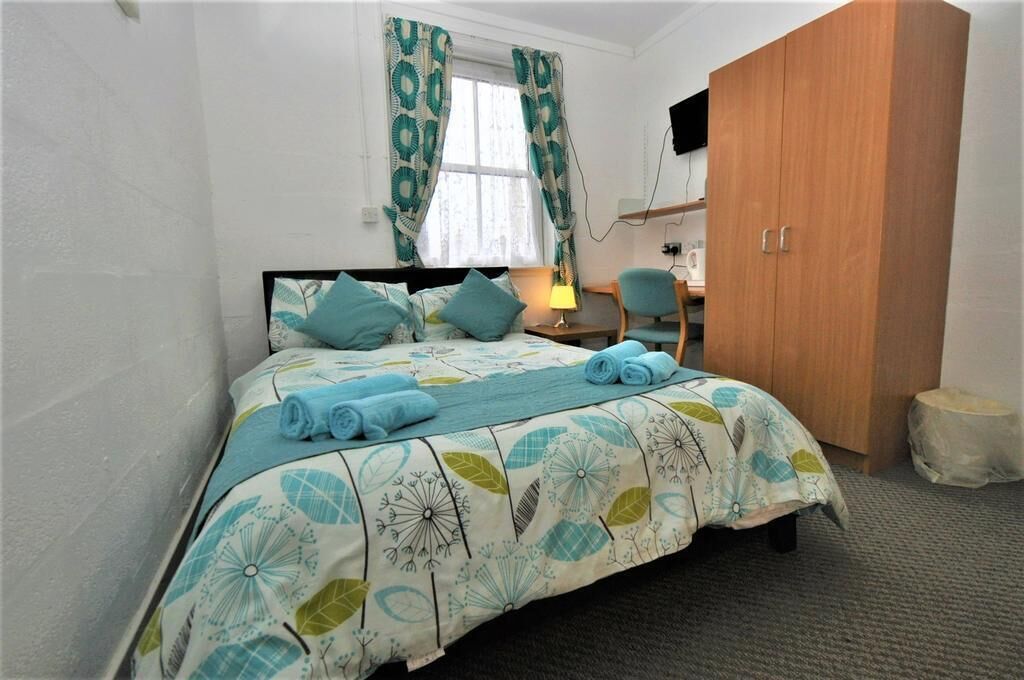 A bedroom with a bed, a desk, a chair, and a wardrobe.