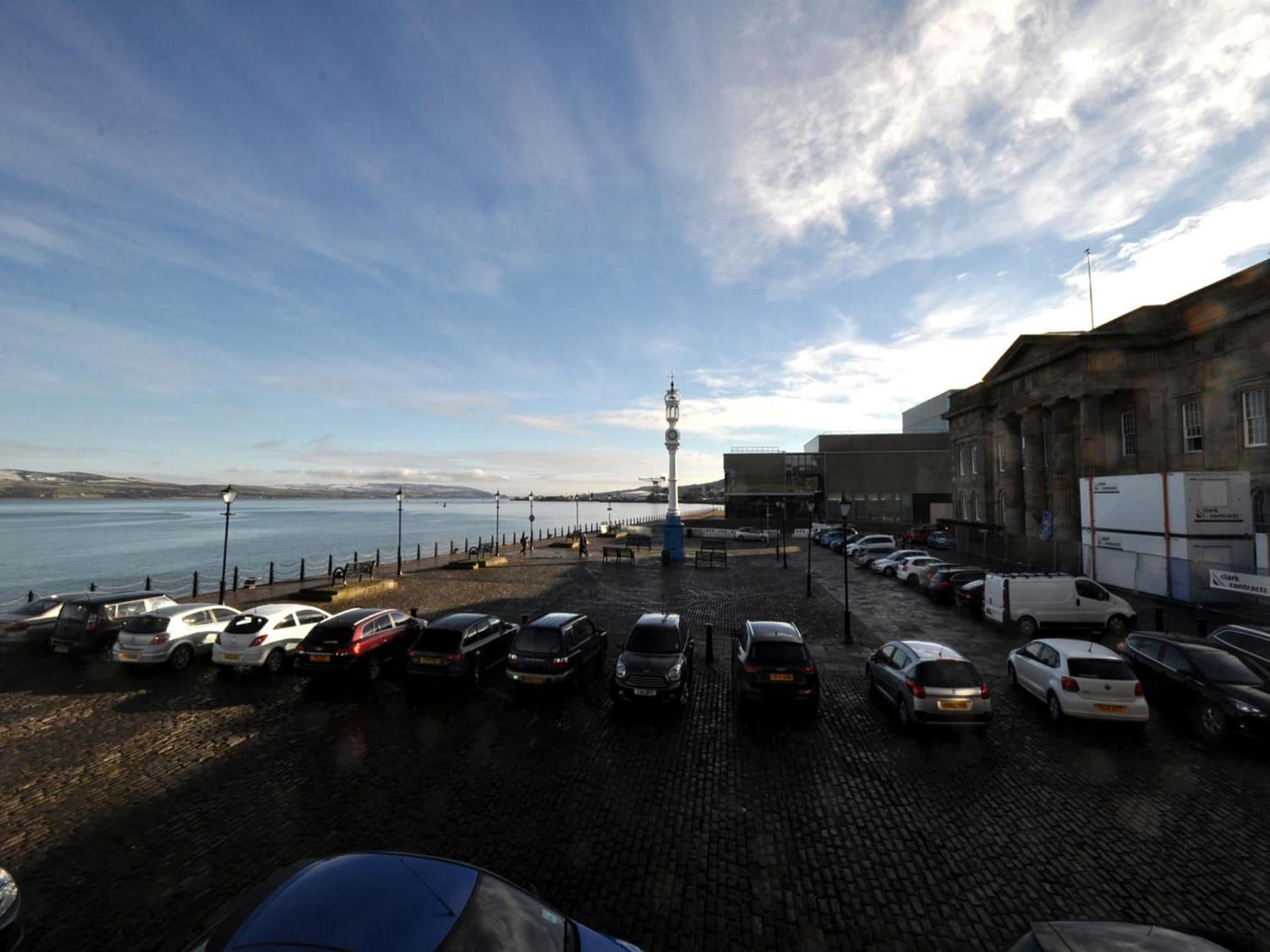 Un estacionamiento con coches, un faro y un edificio con señalización.