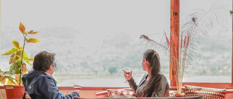Two people seated at a table with a view of a landscape.