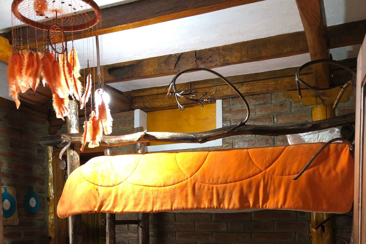 A rustic wooden bunk bed with an orange bedspread and white pillows.