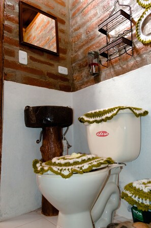 A bathroom with a white toilet, a wooden sink, and a mirror on the wall. - Alojamiento Vertientes del Imbabura (San Pablo del Lago)