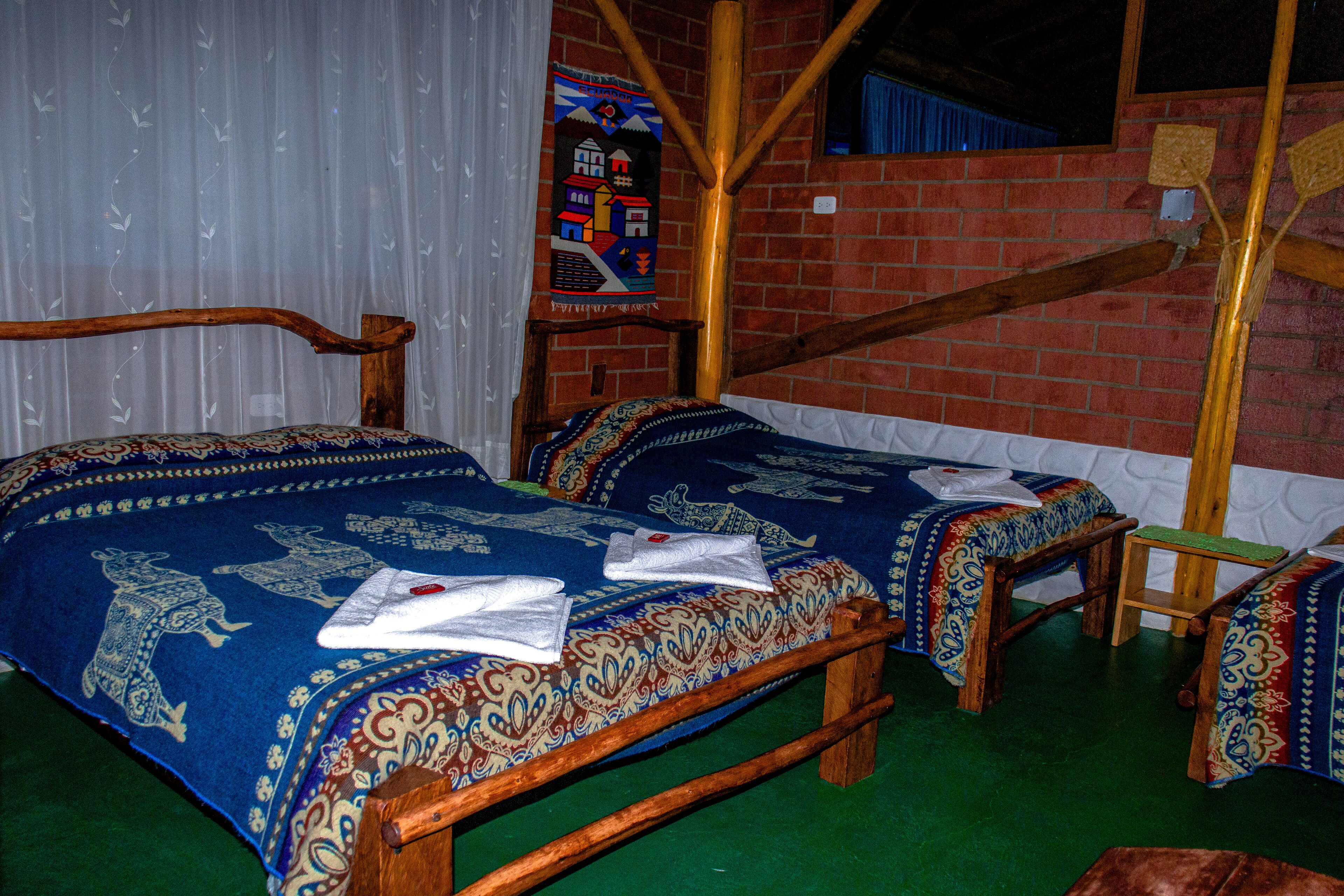 A traditional room with two wooden beds, each with patterned bedding and towels.