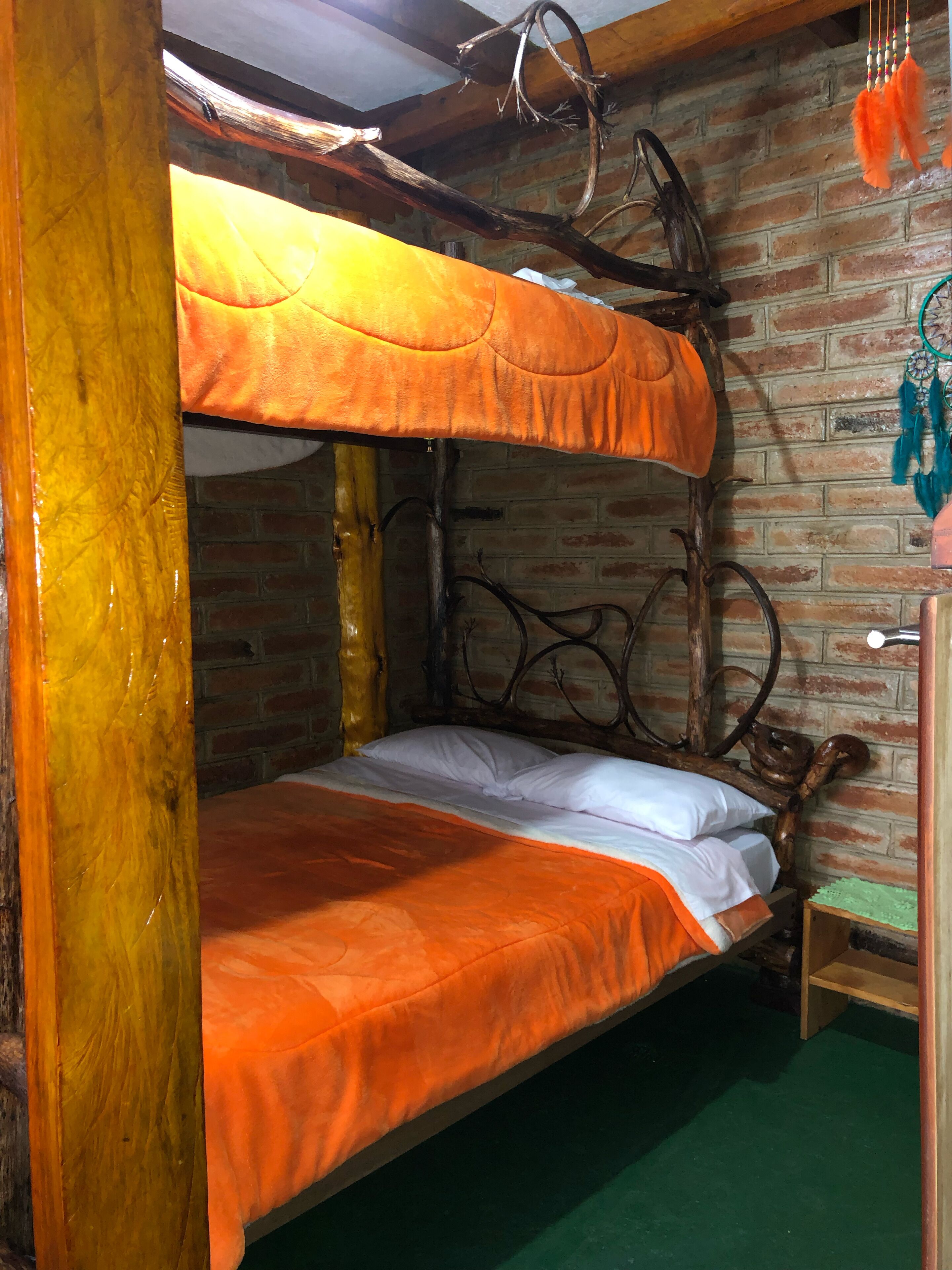 A bunk bed with a wooden headboard and a brick wall background.