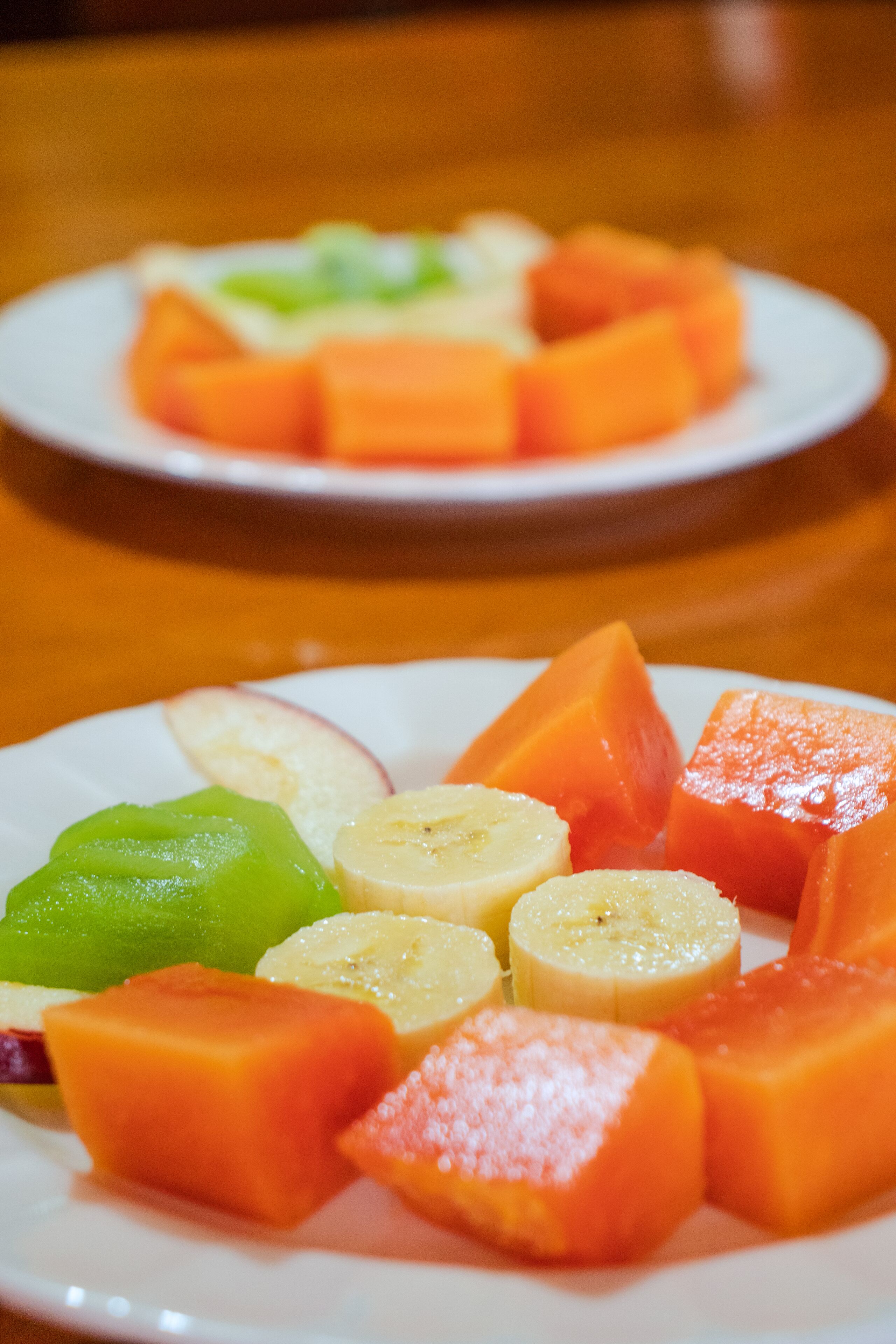 Un plato de frutas cortadas, incluyendo melón, plátano y manzana.