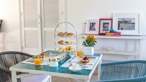 A breakfast table with a three-tiered stand, a potted plant, and framed pictures on a shelf in the background. - Suite Time Capri Villa La Pergola (Capri)