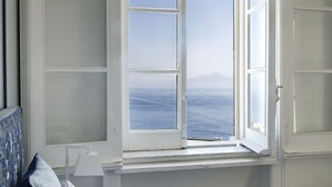 A bedroom with a large window, a bed with blue bedding, and a star-shaped throw pillow. - Suite Time Capri Villa La Pergola (Capri)