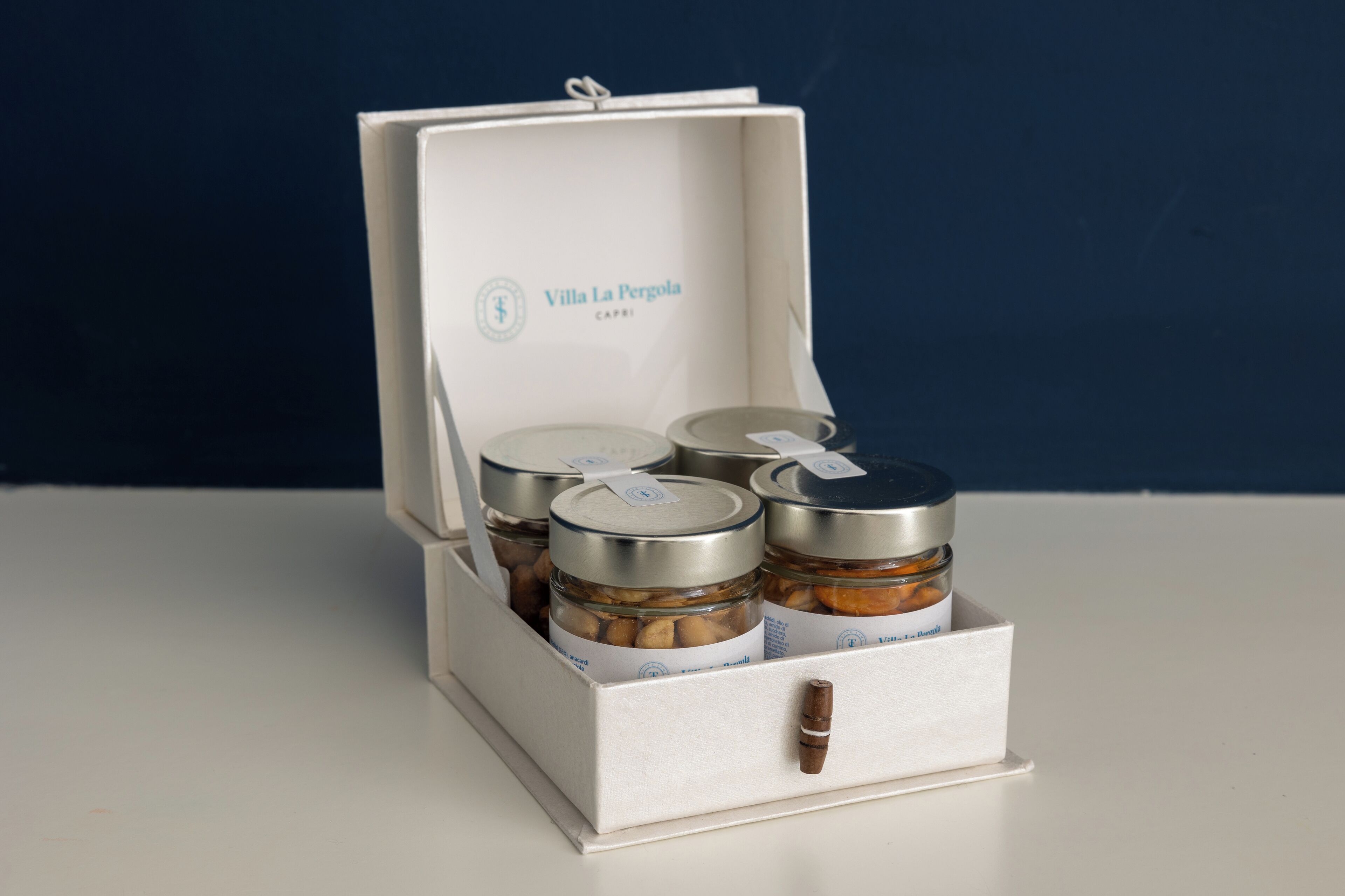 A white box with a label "Villa La Pergola Capri" containing three jars with metal lids.