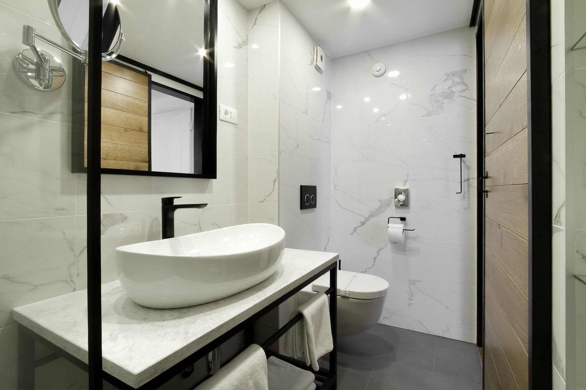 A modern bathroom with a large white sink, a mirror, and a toilet.