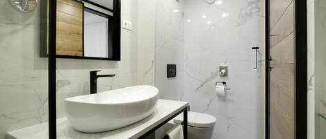 A modern bathroom with a large white sink, a mirror, and a toilet.