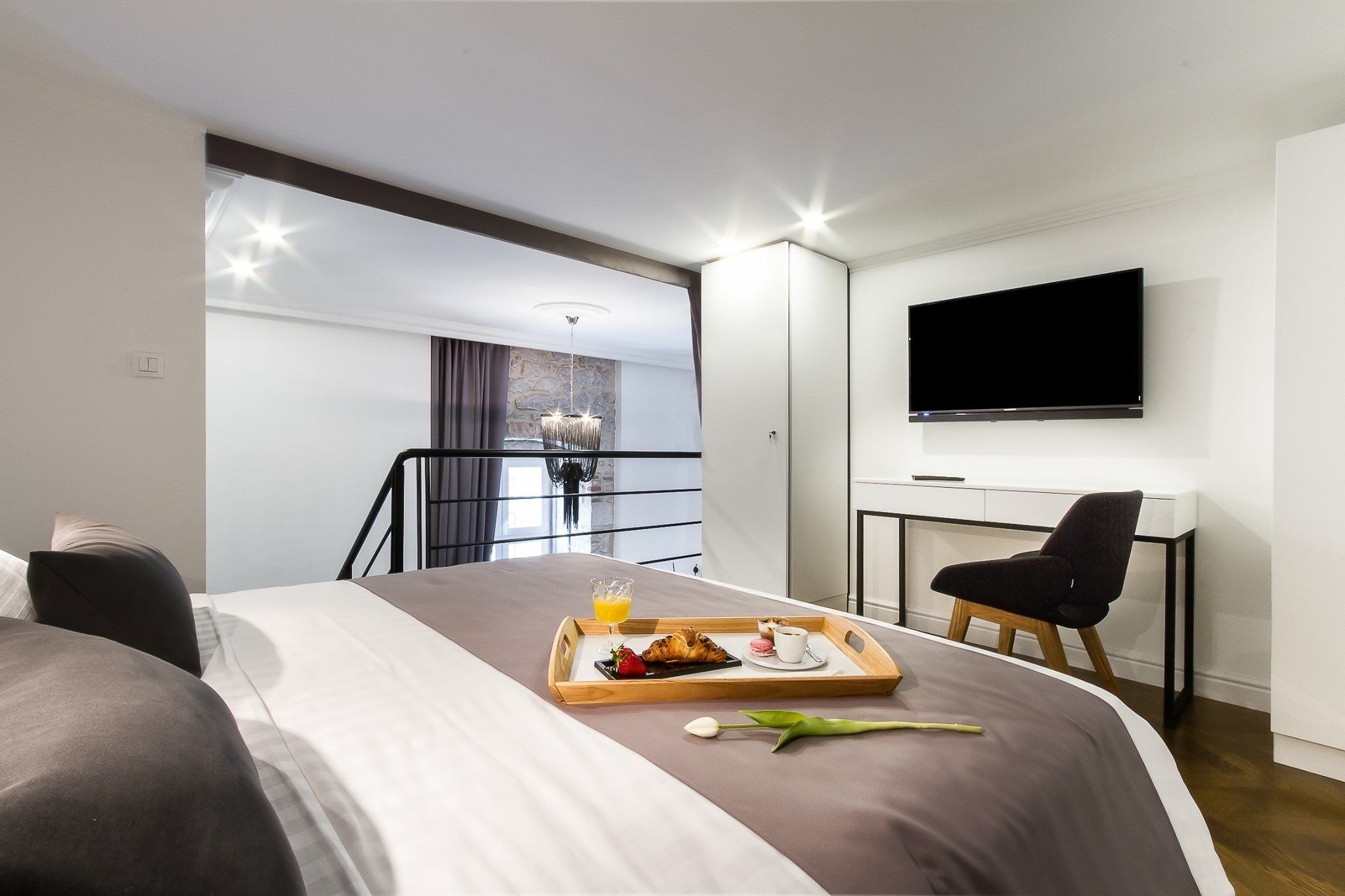 A hotel room with a bed, breakfast tray, TV, and a desk.