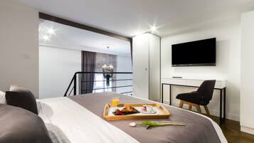 A hotel room with a bed, breakfast tray, TV, and a desk.