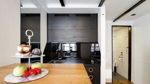 A modern kitchen with a wooden table, a fruit platter, and a chocolate dessert. - DeZign Apartments (Zadar)