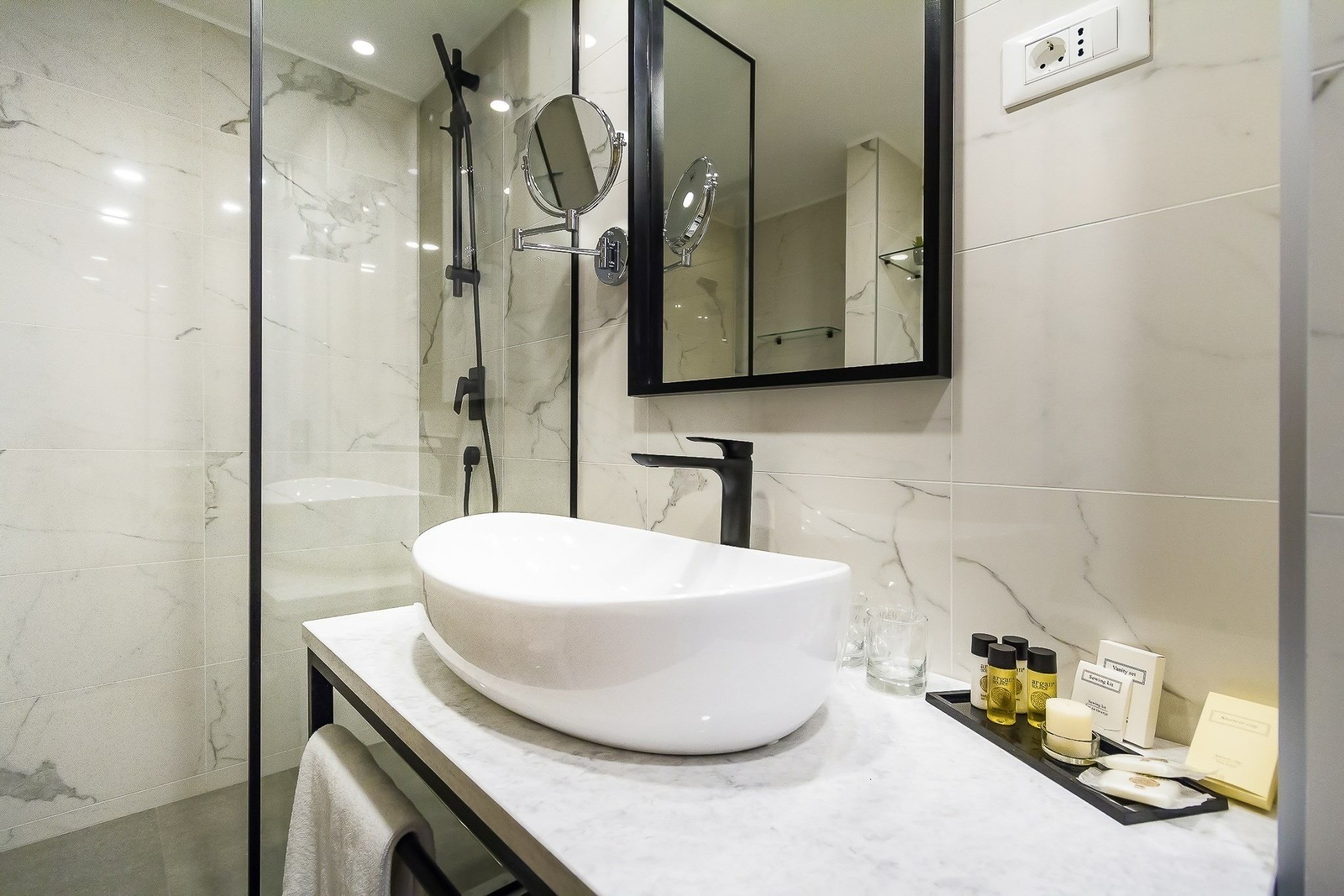 A modern bathroom with a large white sink, a mirror, and a glass-enclosed shower.