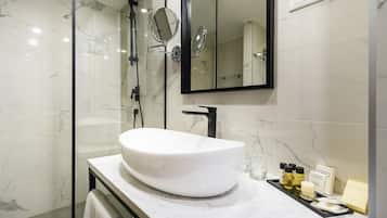A modern bathroom with a large white sink, a mirror, and a glass-enclosed shower.