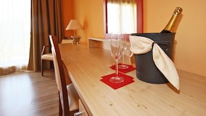 Een hotelkamer met een houten eettafel, twee wijnglazen, een champagnefles en een rode servet.