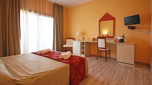 Een hotelkamer met een bed, een bureau, een stoel, een televisie en een minibar.