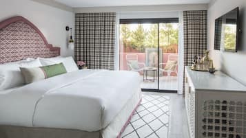 A hotel room with a bed, a desk, a chair, and a view of the outdoors.