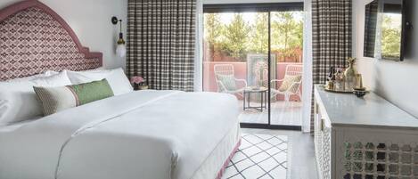 Habitación de hotel con cama, escritorio, silla y vistas al exterior.