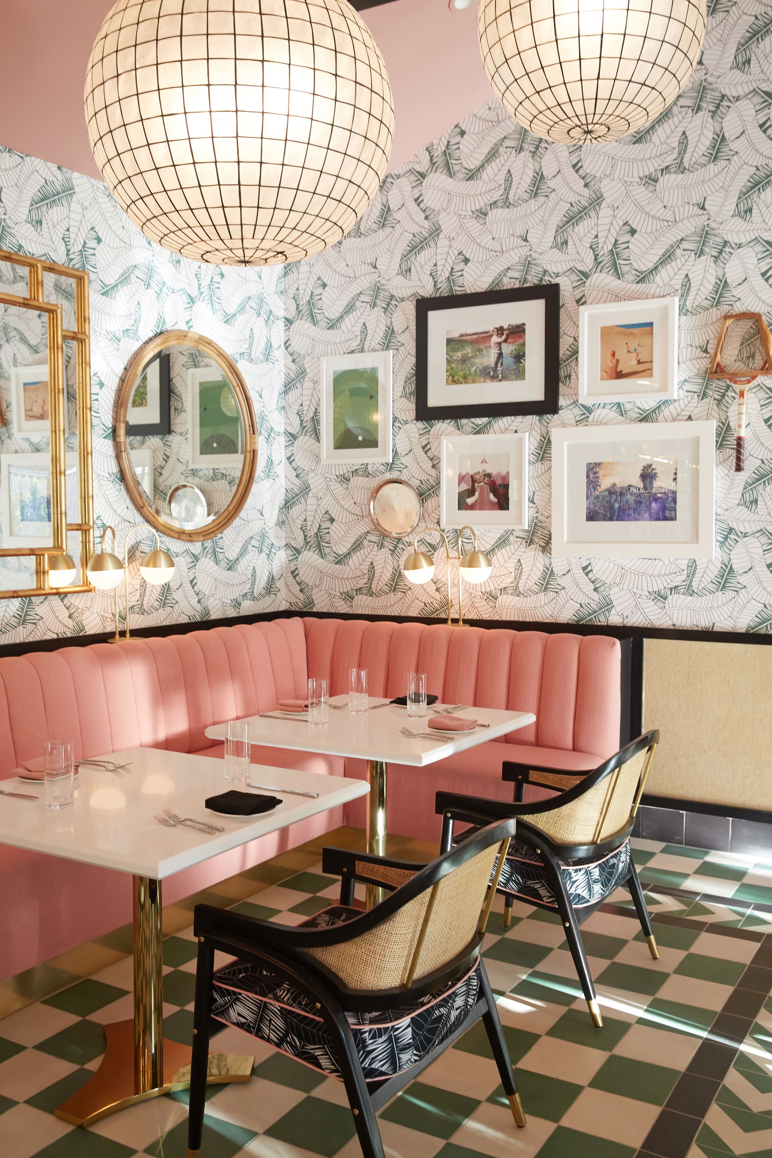 A restaurant with a pink booth seating area, white tables, and checkered flooring.