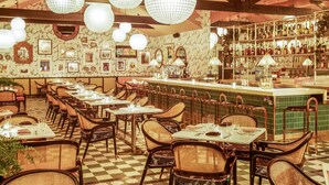 A restaurant with checkered flooring, wicker chairs, and a bar area with shelves of bottles. - Sands Hotel and Spa (Indian Wells)